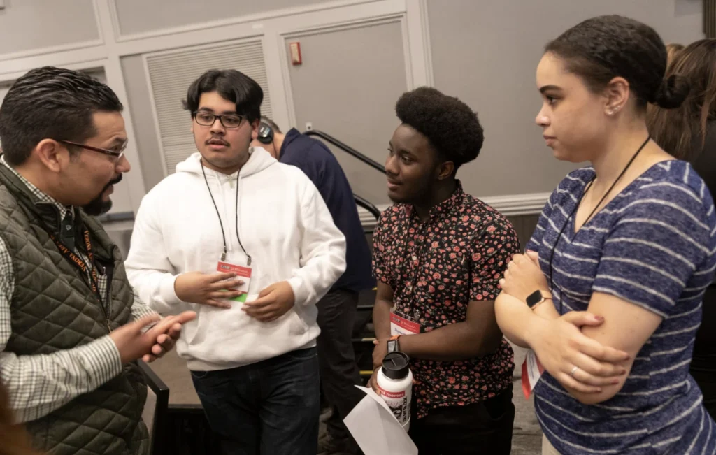 Three students speaking with a mentor.