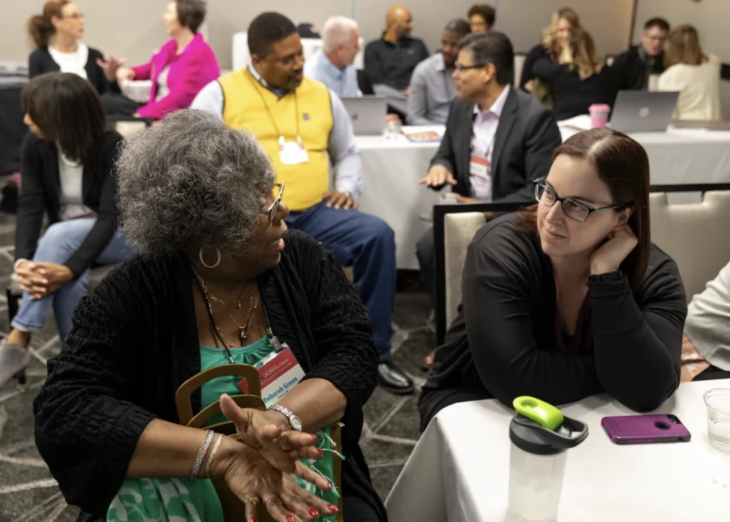 Two institute attendees sitting next to each other and having a discussion.